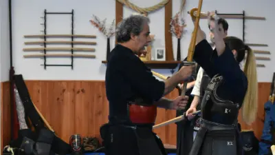 Profesor de kendo corrigiendo la postura de kamae a una alumna en el dojo