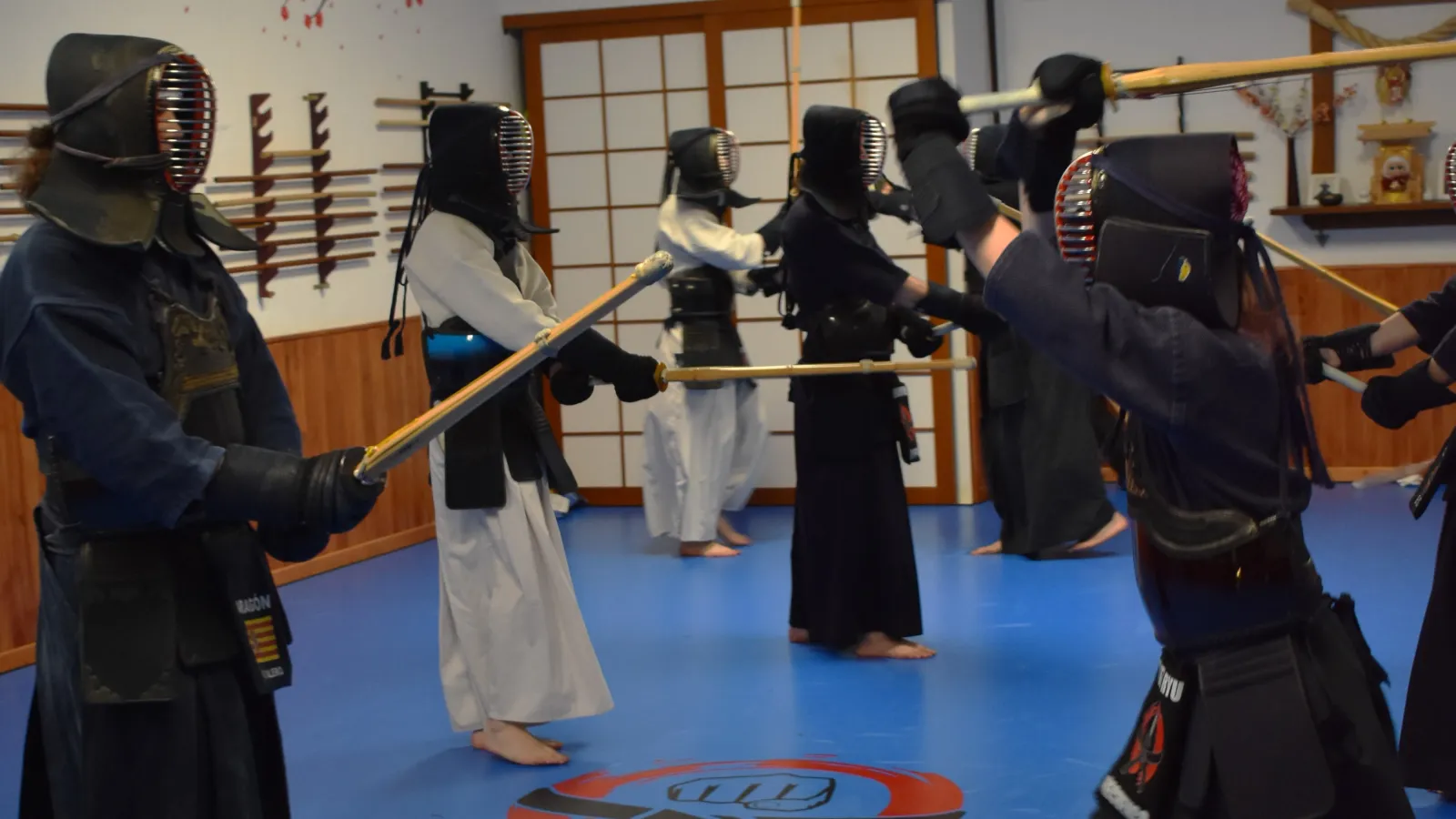Grupo de practicantes de kendo con bogu enfrentados por parejas durante una clase